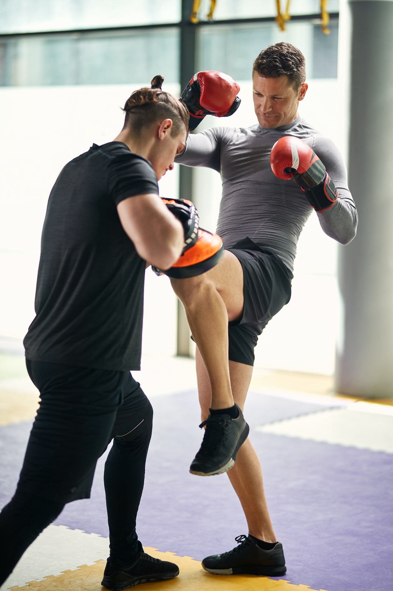 Dedicated Athletic Man Having Kickboxing Training With His Coach In A Gym.
